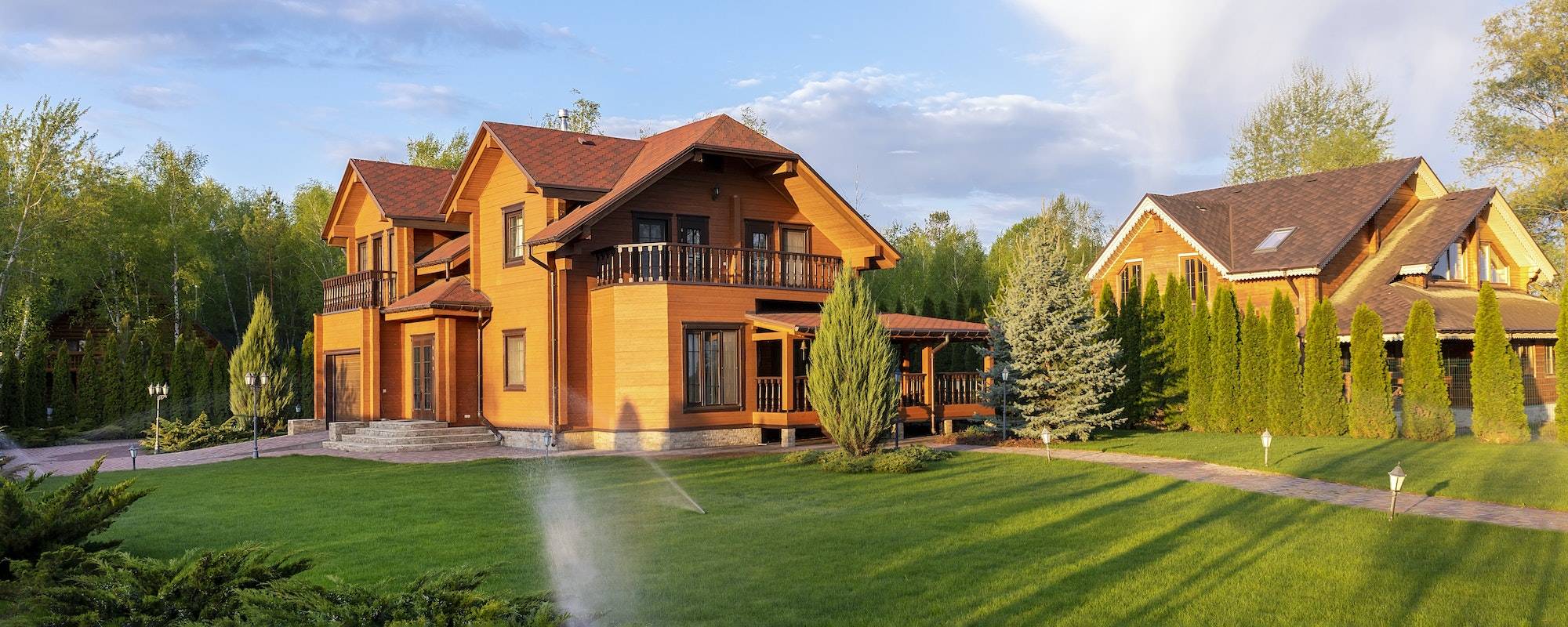 Modern wooden eco house villa facade luxury big house. Timber cottage with with green lawn water